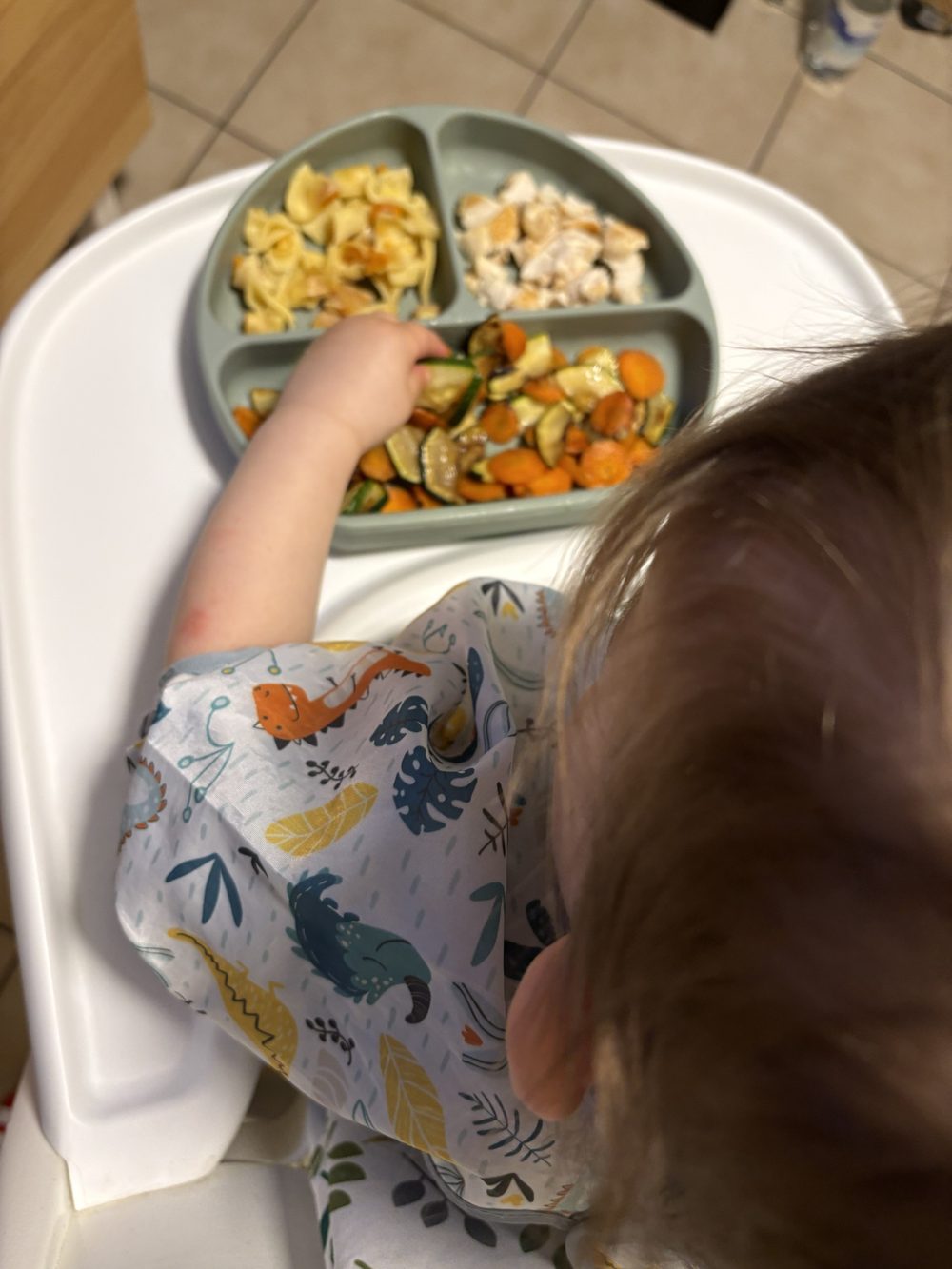 Kind isst Nudeln, Hähnchen und Gemüse vom Teller
